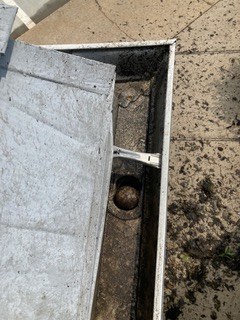Gutter section showing bracket and downspout outlet during repair work
