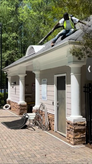 Technician clearing debris from a roof with a backpack blower